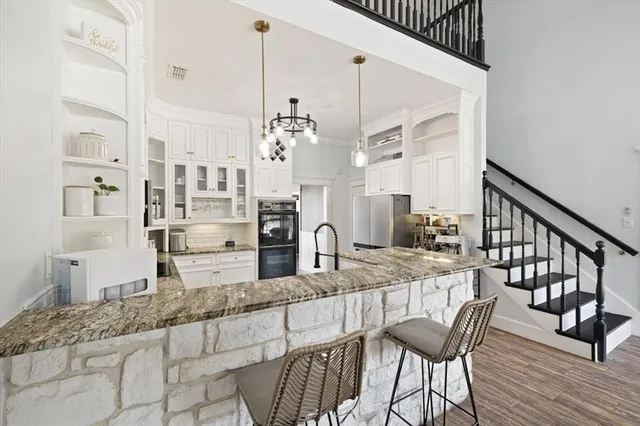 a kitchen with stainless steel appliances kitchen island granite countertop a table chairs in it and wooden floors