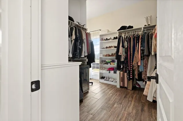 a view of walk in closet with clothes and shoes