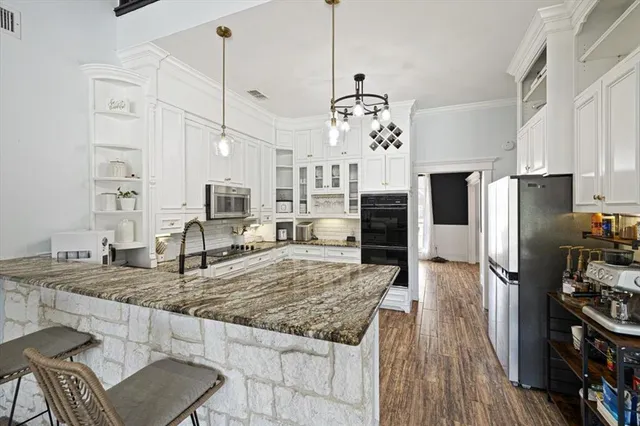 a kitchen with stainless steel appliances granite countertop a stove refrigerator and wooden floor