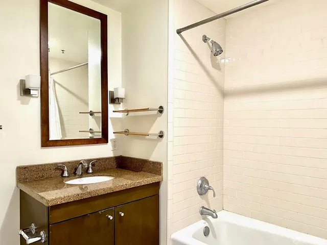a bathroom with a granite countertop sink a mirror and a bathtub