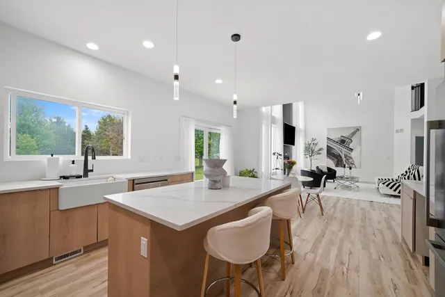 a open kitchen with stainless steel appliances granite countertop a refrigerator a sink dishwasher a stove and a dining table with wooden floor