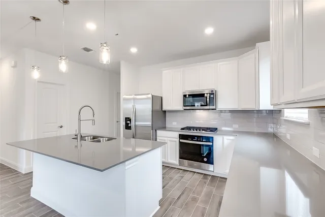 a kitchen with stainless steel appliances granite countertop a sink a window and white cabinets