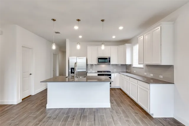 a kitchen with kitchen island a sink stainless steel appliances and cabinets
