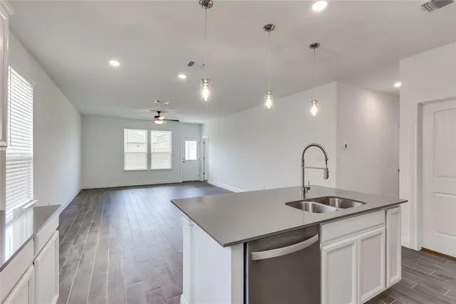 a large kitchen with stainless steel appliances a large counter top a stove a refrigerator and white cabinets