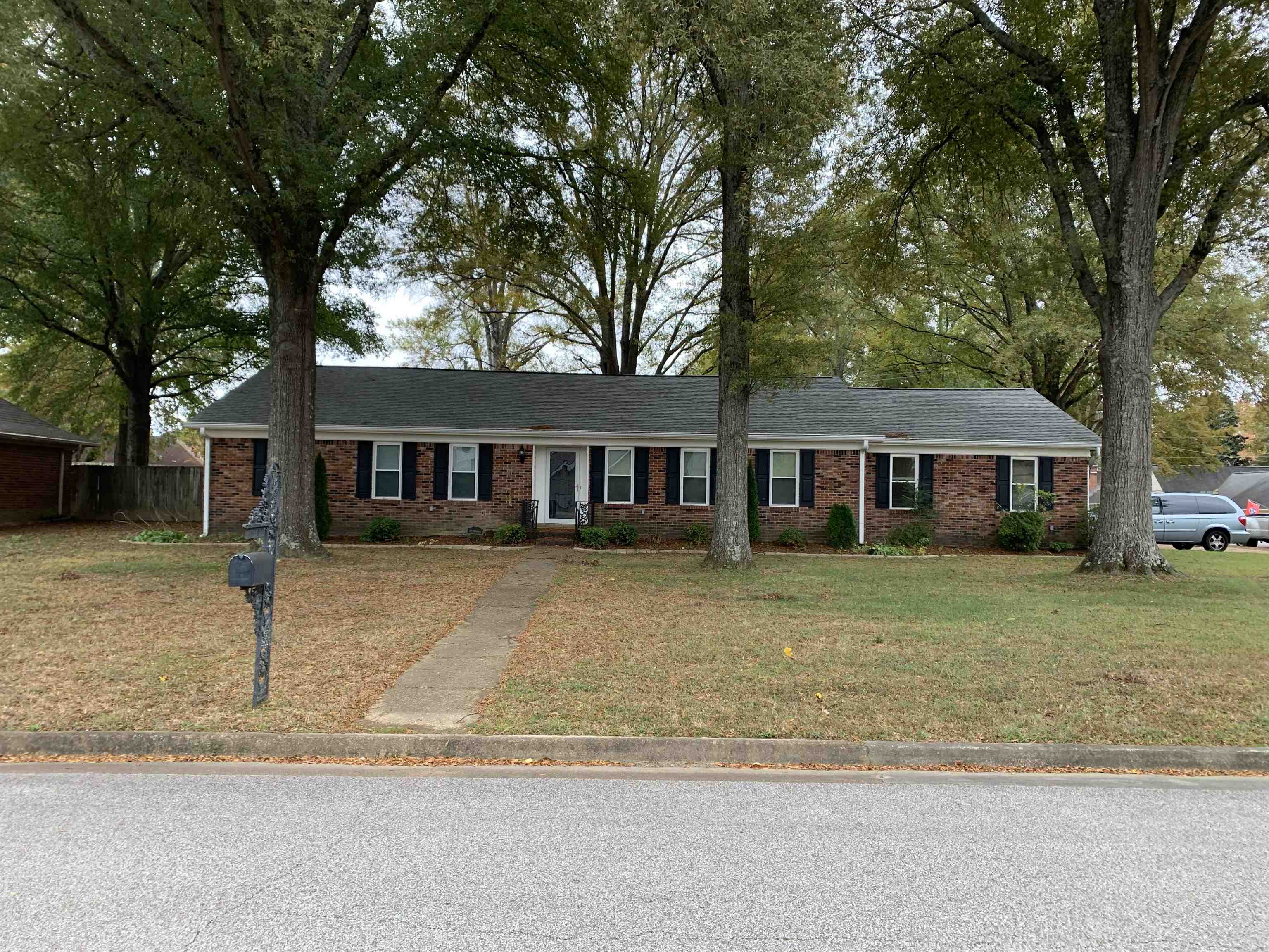 a front view of a house with a garden and trees
