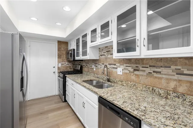 a kitchen with stainless steel appliances granite countertop a sink and a refrigerator
