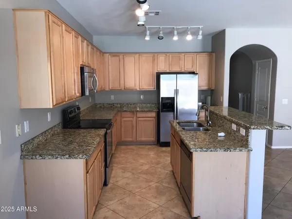 a kitchen with kitchen island granite countertop a sink counter top space appliances and cabinets