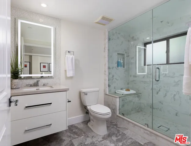 a bathroom with a toilet a sink a glass door a shower a mirror and vanity