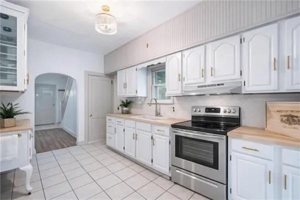 a kitchen with stainless steel appliances granite countertop a stove a sink and a white cabinets