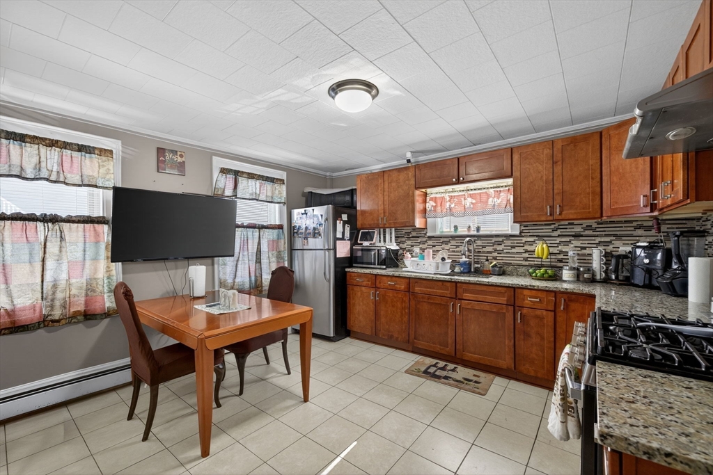 a kitchen with stainless steel appliances granite countertop a stove top oven a sink a dining table and chairs with wooden floor
