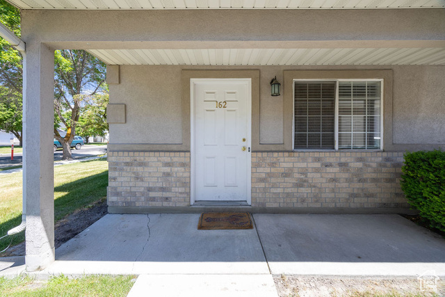 View of exterior entry featuring brick siding and stucco siding