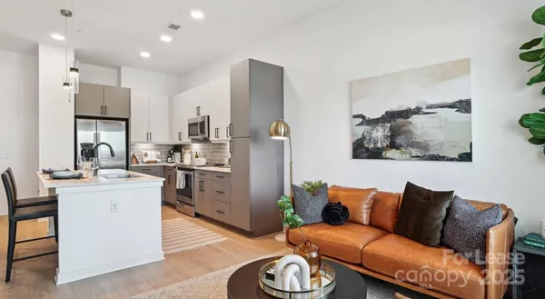 a living room with stainless steel appliances furniture and a kitchen view