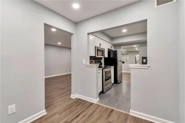 a living room with stainless steel appliances kitchen island granite countertop a refrigerator and a sink