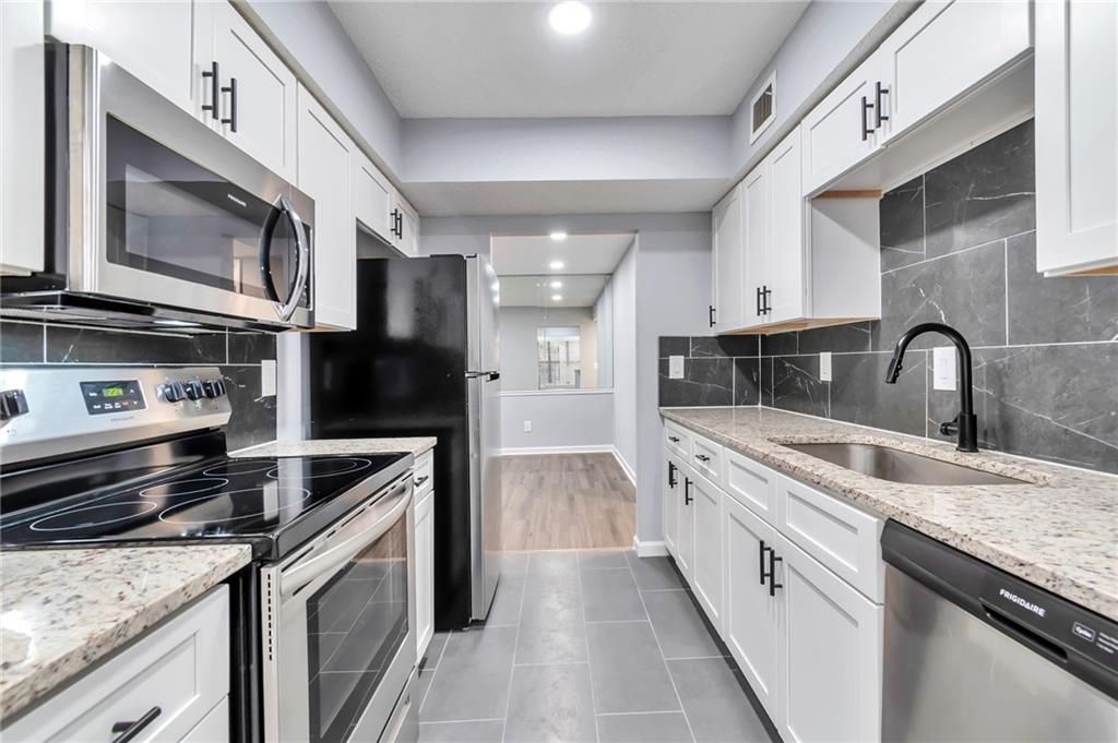 1502 Huntingdon Chase Atlanta, GA 30350 - Photo 6 of 29 a kitchen with stainless steel appliances granite countertop a stove microwave and sink