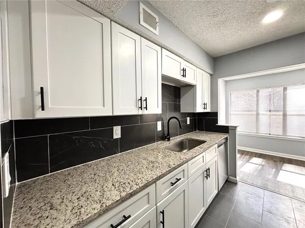 a kitchen with granite countertop a sink and a stove