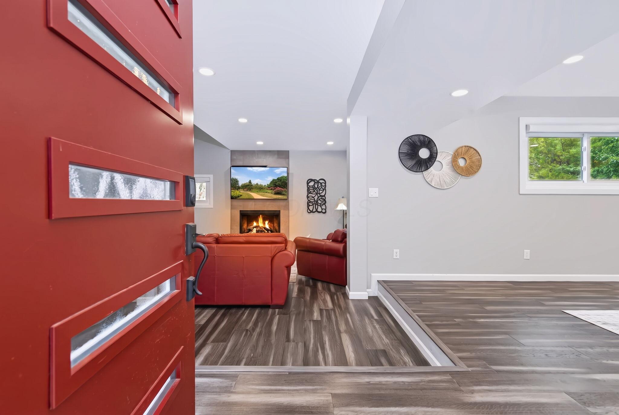 7140 Cook Road Powell, OH 43065 - Photo 32 of 87 Red entry door with multiple glass inserts, wood-finish flooring, recessed lighting, and a stone-clad fireplace