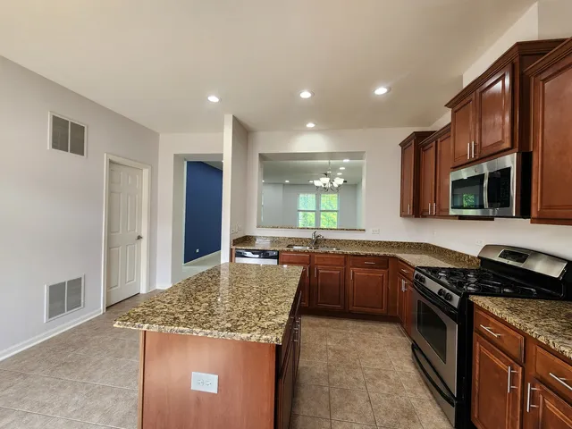 a kitchen with kitchen island granite countertop a stove refrigerator and microwave