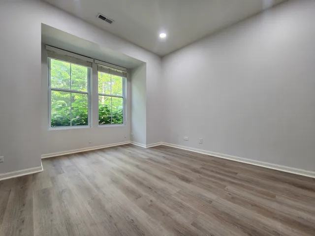 an empty room with wooden floor and windows