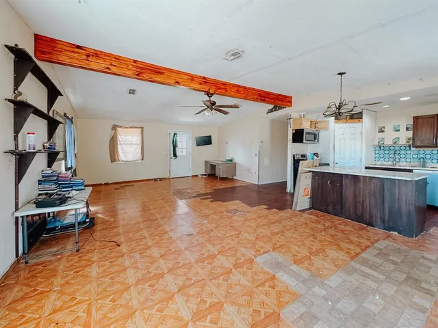 an empty room with wooden floor ceiling fan and windows
