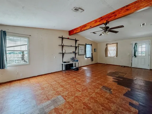 a view of empty room with wooden floor and fan