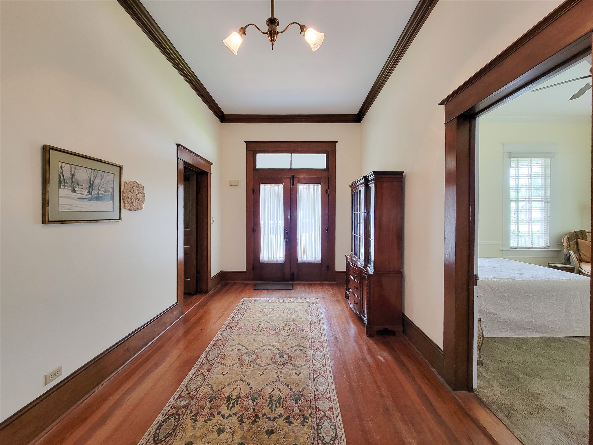 1406 Key Street Brenham, TX 77833 - Photo 6 of 50 Step into a stunning foyer with elegant antique hardwood floors, timeless architecture, soaring 11-foot ceilings, and original brass chandeliers.