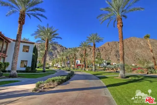 a view of a swimming pool with a table and chairs under palm trees