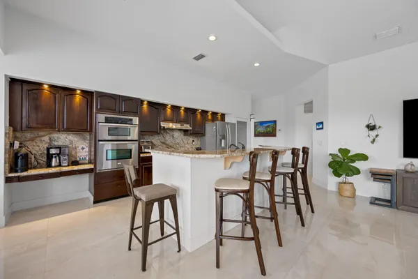 a kitchen with stainless steel appliances kitchen island granite countertop dining table chairs and sink