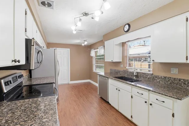 a kitchen with granite countertop a refrigerator and a sink