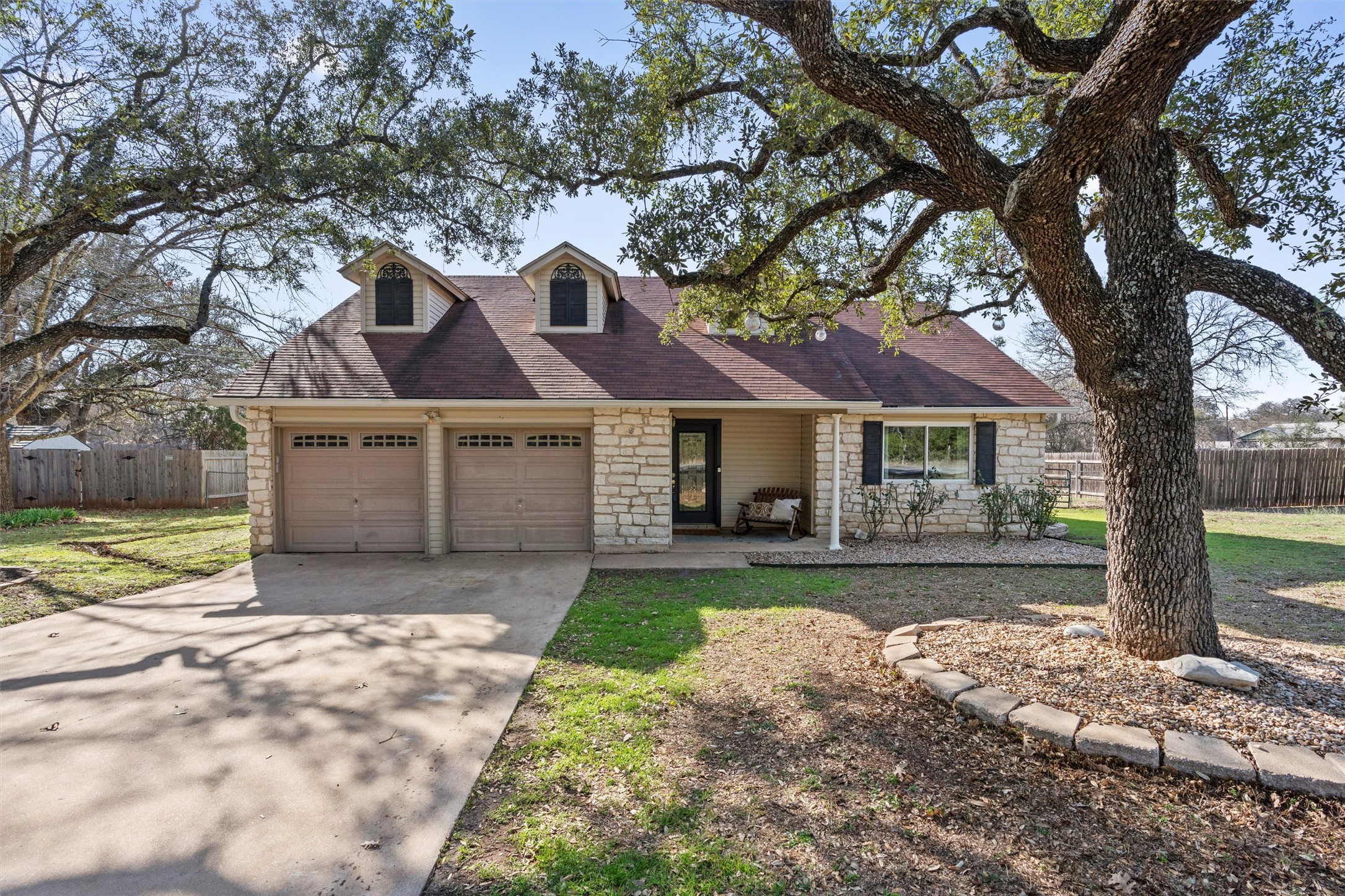 3431 Bliss Spillar Road Manchaca, TX 78652 - Photo 1 of 30 View of front of property with stone siding, concrete driveway, a garage, a porch, and roof with shingles