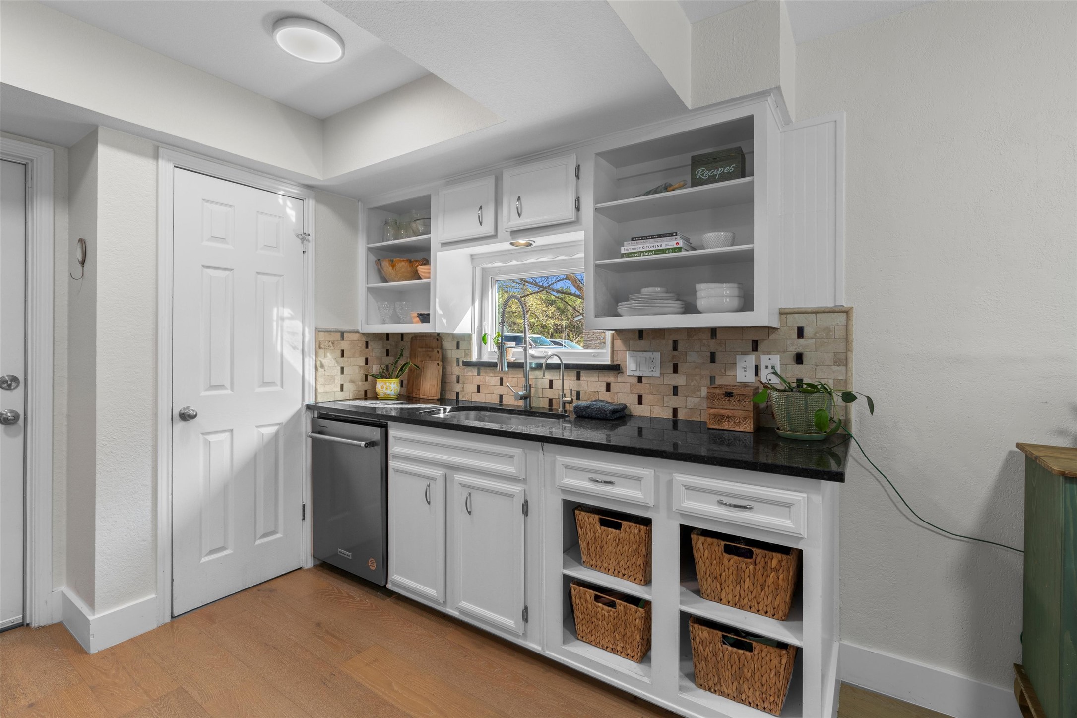 3431 Bliss Spillar Road Manchaca, TX 78652 - Photo 9 of 30 Bar area featuring white cabinets, open shelves, light wood-style flooring, stainless steel dishwasher, and backsplash