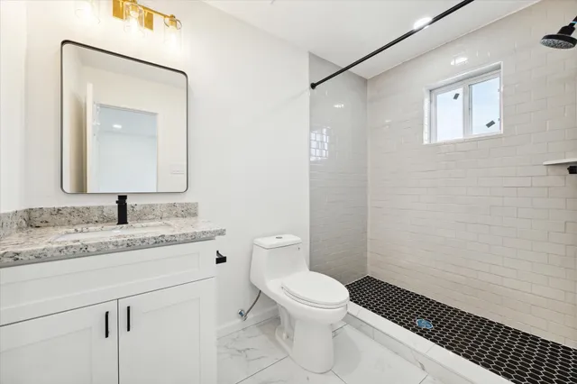 a bathroom with a granite countertop sink mirror vanity and toilet