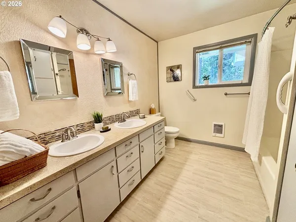 a spacious bathroom with a double vanity sink a mirror and a shower