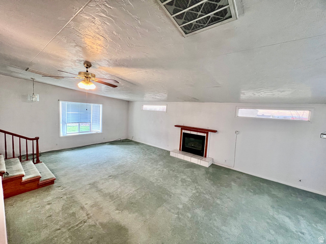 479 East 100 N Road Meadow, UT 84644 - Photo 6 of 59 Unfurnished living room featuring a tile fireplace, carpet, and a ceiling fan