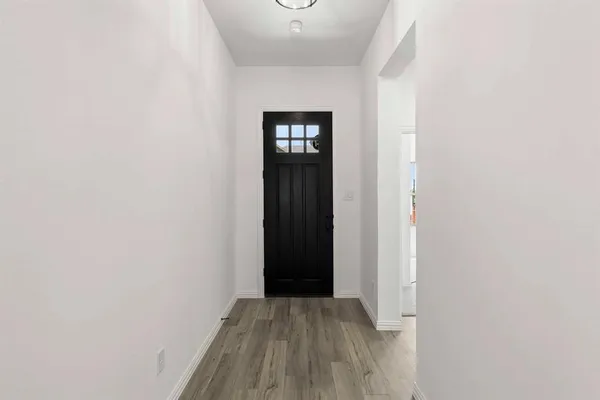a view of an empty room with wooden floor and closet