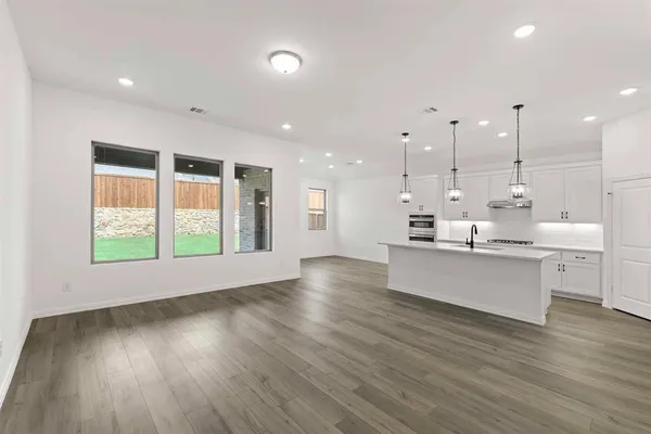 a large white kitchen with large window wooden floor and stainless steel appliances