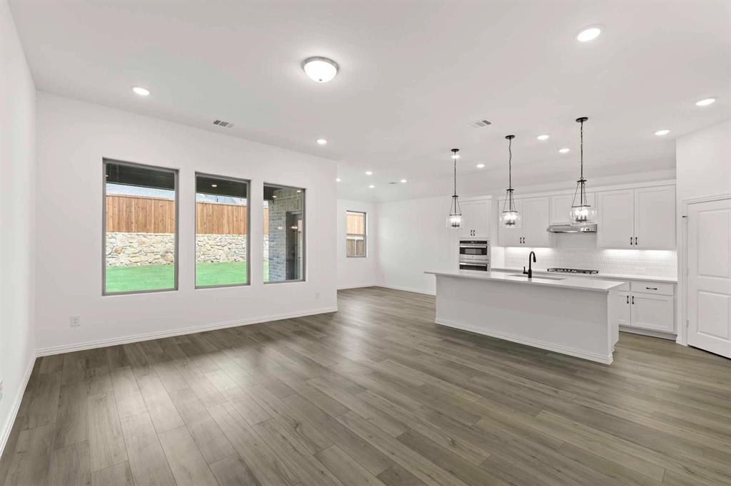 1909 Wishon Road Celina, TX 75009 - Photo 26 of 40 a large white kitchen with large window wooden floor and stainless steel appliances