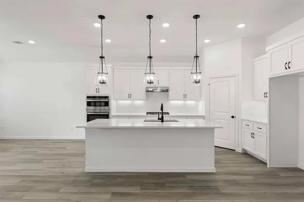 a large kitchen with stainless steel appliances kitchen island a large stove a refrigerator a sink and white cabinets