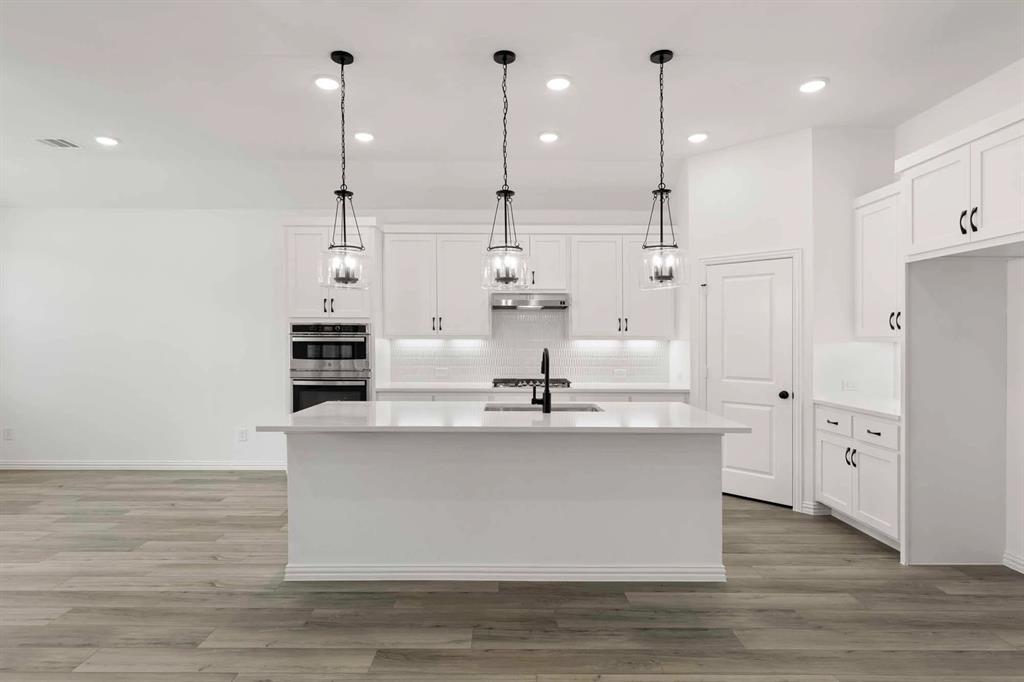 1909 Wishon Road Celina, TX 75009 - Photo 27 of 40 a large kitchen with stainless steel appliances kitchen island a large stove a refrigerator a sink and white cabinets