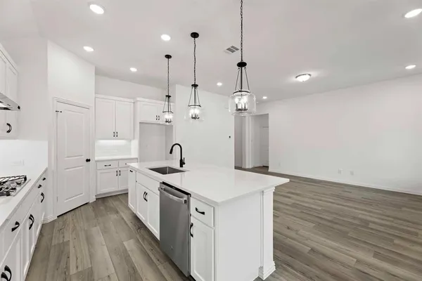 a kitchen with a sink a stove a refrigerator and white cabinets