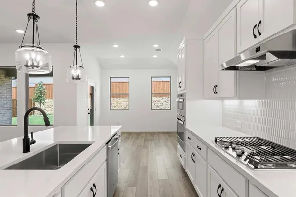 a kitchen with granite countertop a stove a sink a refrigerator and a wooden floor