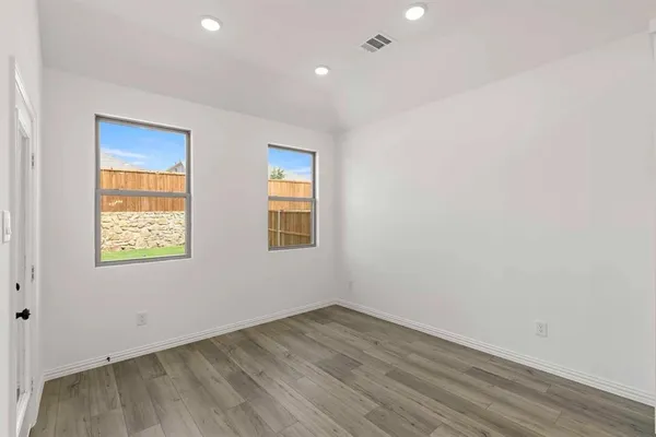 an empty room with wooden floor and windows