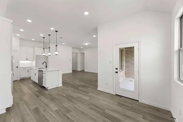 a large white room with kitchen island stainless steel appliances wooden floor and a window