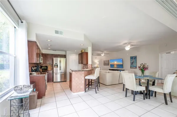 a living room with stainless steel appliances furniture a rug and a kitchen view