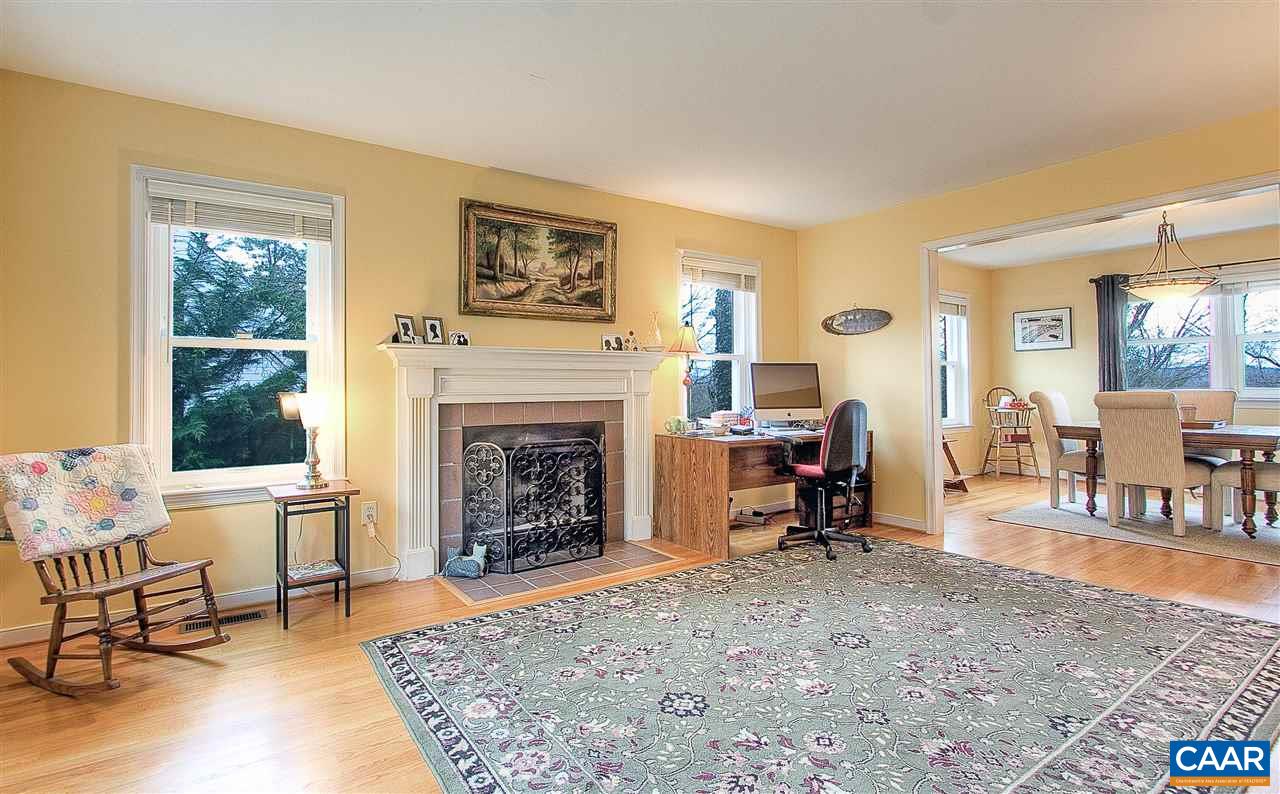1532 Dairy Road Charlottesville, VA 22903 - Photo 15 of 42 The spacious living room is connected to the dining room by a large framed opening, facilitating easy flow for more formal entertaining. The wood burning fireplace with brick surround is framed by an elegant mantel with fluted trim.