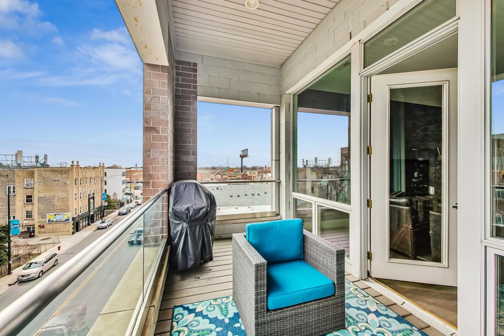 4042 North Pulaski Road, Unit 4E Chicago, IL 60641 - Photo 29 of 32 a view of a balcony with couches wooden floor and a floor to ceiling window