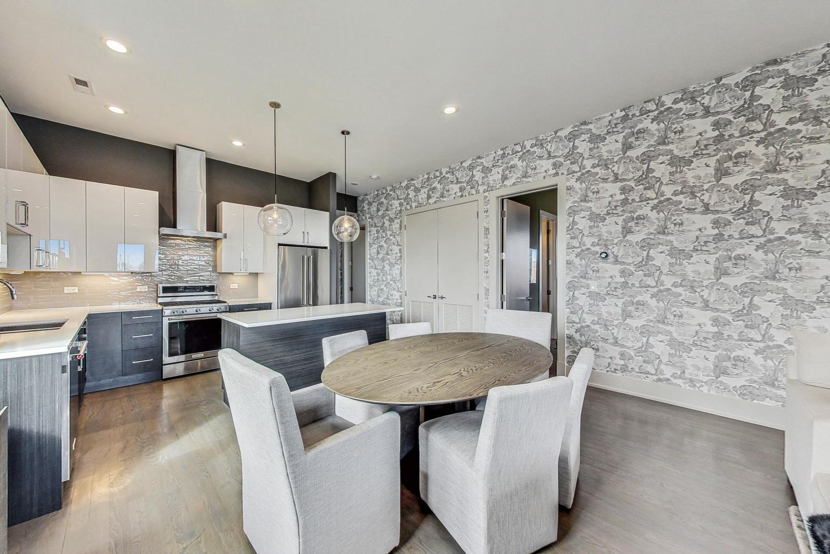 4042 North Pulaski Road, Unit 4E Chicago, IL 60641 - Photo 7 of 32 a kitchen with stainless steel appliances kitchen island granite countertop a table chairs microwave and cabinets