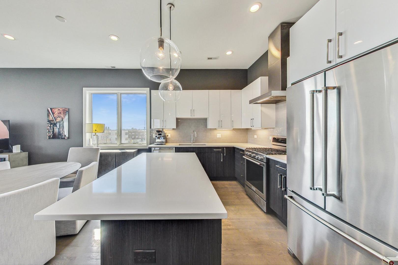 4042 North Pulaski Road, Unit 4E Chicago, IL 60641 - Photo 10 of 32 a large kitchen with stainless steel appliances a large counter top a stove a chimney a refrigerator and a sink