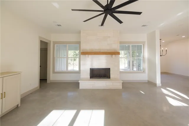 a view of a livingroom with a fireplace a ceiling fan and windows