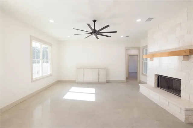 an empty room with windows and fireplace