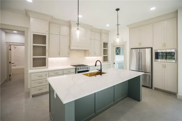 a kitchen with a sink a stove a refrigerator and white cabinets